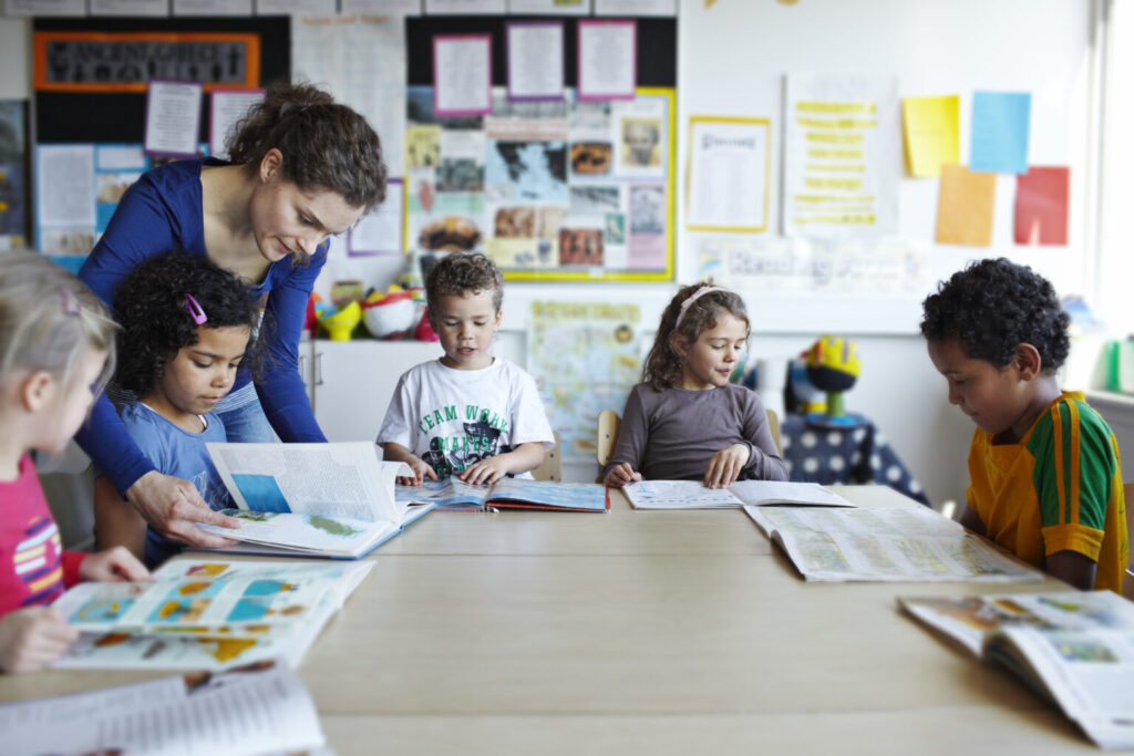Teacher looking in books with children Shot school classroom